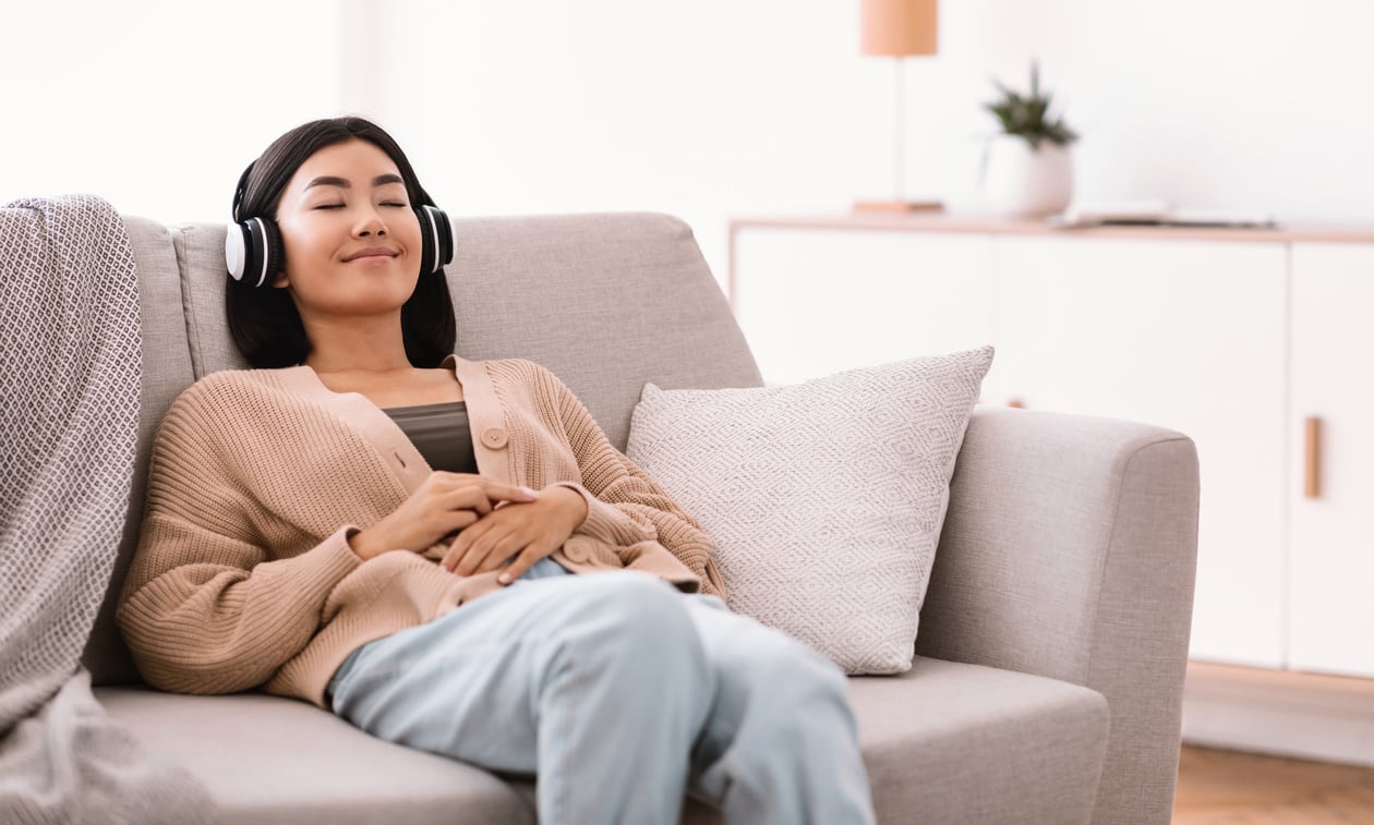 Calm asian woman listening to music wearing headphones