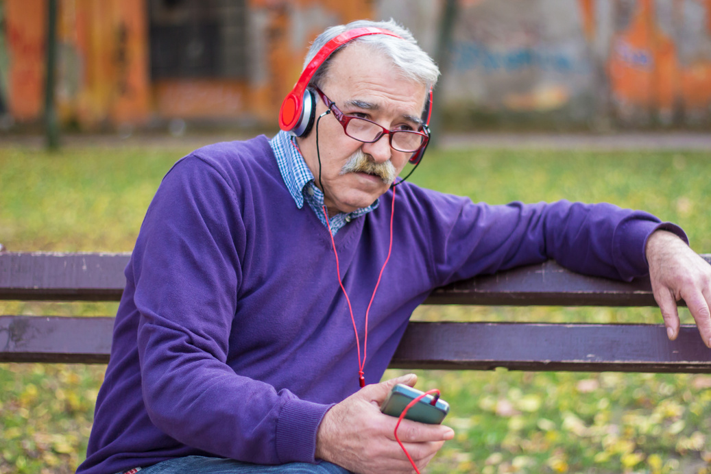 Older man with headsets listening music.