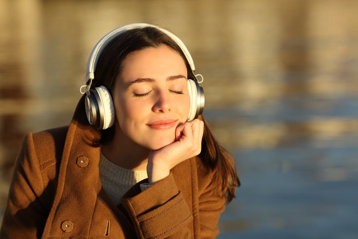 Woman listening to music relaxing at sunset in winter